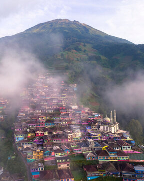 Aerial view of a colorful village with a majestic mosque and misty mountains at sunrise, Nepal Van Java, Indonesia.