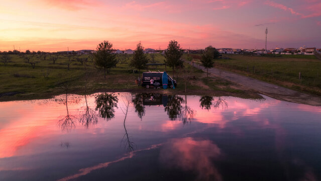 Aerial view of a serene lake at sunset with reflections and a camper, Odivelas, Portugal.