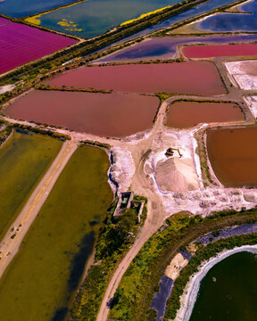 Aerial view of colorful salt pans and salinas with a crane in the wetlands, Olhao, Portugal.
