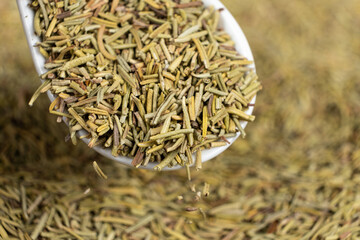 Rosemary seasoning pours out of spoon, macro texture.