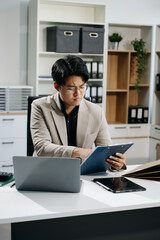 Young business man working at office with laptop, tablet and taking notes on the paper..