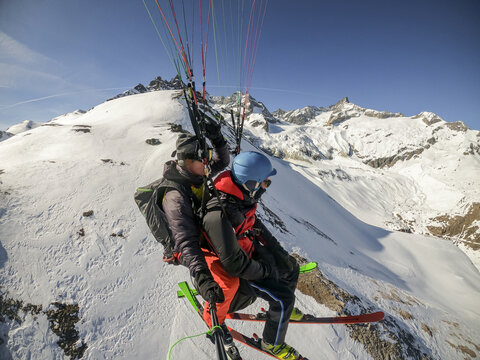 Exciting tandem paragliding over snowy mountain peaks