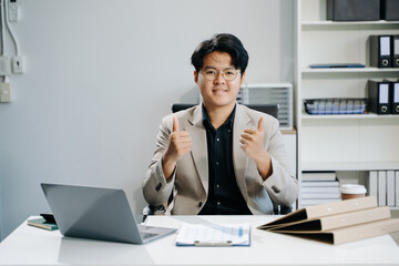 Young business man working at office with laptop, tablet and taking notes on the paper..