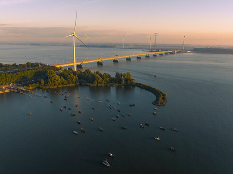 Aerial view of beautiful sunrise over fishing boats and wind turbines in Haringvliet, Ooltgensplaat, South Holland, Netherlands.