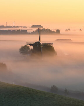 Aerial view of a traditional windmill surrounded by fog at sunrise, Workum, Netherlands.