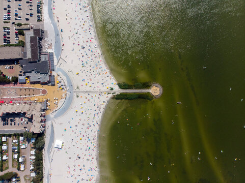 Aerial view of a beautiful sandy beach by the ijsselmeer lake on a sunny summer day with people enjoying relaxation, Makkum, Netherlands.