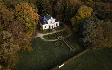 Aerial view of a beautiful house surrounded by a serene forest in autumn sunset, Oudemirdum, Netherlands.