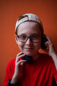 Young boy in red outfit with headphones against orange wall