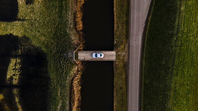 Aerial view of serene countryside with a bridge and road alongside a canal, Workum, Friesland, Netherlands.