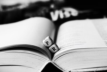 Public relations - book with open pages with cube letters black and white