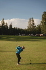 Golfer swings at sunset on a lush course surrounded by trees in a calm