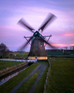 Aerial view of a serene windmill at sunrise with a picturesque canal and charming countryside, Workum, Netherlands.