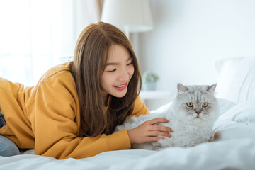 Happy asian woman hugging with fluffy grey cat with relax on the bed at home, A touching moment...