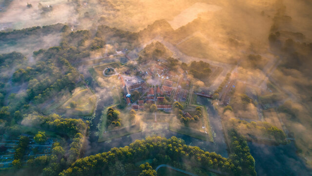 Aerial view of a beautiful fortress and windmill surrounded by fog and forest at sunrise, Bourtange, Groningen, Netherlands.