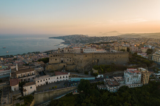 Aerial view of beautiful sunset over the cityscape of Naples with historic castle and picturesque coastline, Vomero Hill, Italy.
