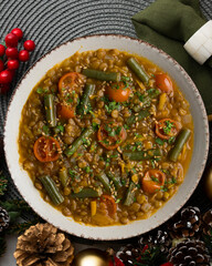 Lentil soup with green beans and cherry tomatoes. Top view table with Christmas decoration.