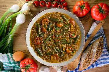 Lentil soup with green beans and cherry tomatoes. Top view table with  decoration.