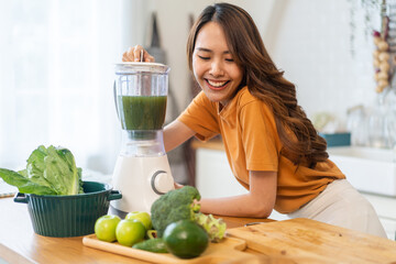 Portrait of beauty healthy asian woman making green vegetables detox cleanse and green fruit smoothie with blender.young girl drinking glass of smoothie, fiber, chlorophyll in kitchen.Diet, healthy