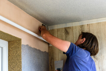 Applying decorative mosaic plaster on the wall.
