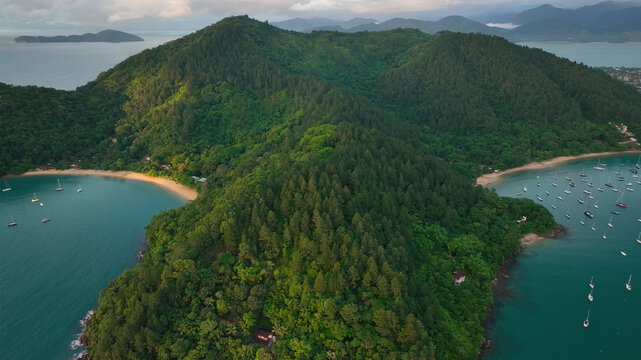 Aerial view of breathtaking tropical forest and sandy beach with boats in the serene bay, Angra dos Reis, Brazil.