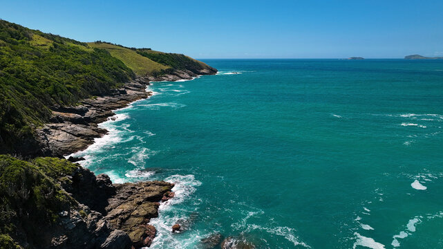 Aerial view of beautiful coastline with rocky cliffs and serene waves, Armacao dos Buzios, Brazil.