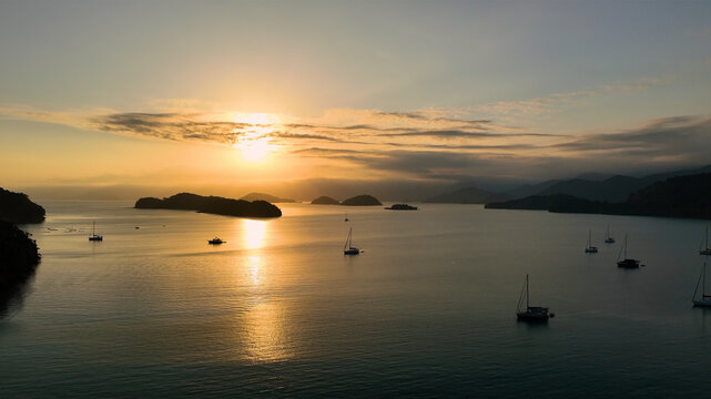 Aerial view of tranquil sunset over the ocean with silhouette of boats and islands, Paraty, Brazil.