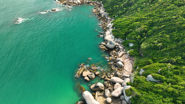 Aerial view of beautiful turquoise water and lush greenery along the rocky shore, Balneario Barra do Sul, Brazil.