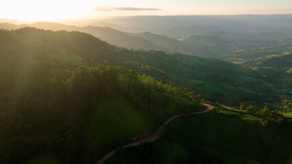 Aerial view of lush green mountains and a tranquil valley at sunset, Monte Verde, Brazil.