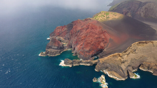 Aerial view of a breathtaking volcanic island with rugged cliffs and azure waters, Capelo, Azores, Portugal.