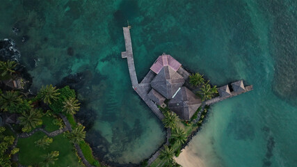Aerial view of a tropical island resort with palm trees and a dock by the turquoise ocean, Sataoauta, Samoa.