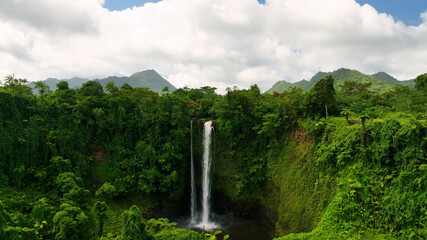 Aerial view of a majestic waterfall cascading through lush greenery and tropical forest, Atua, Samoa.