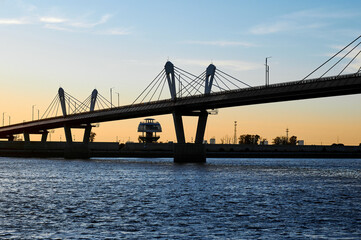 Cross-border bridge on the Amur River between Russia and China. View of the Chinese bank with a spherical observation tower on a summer evening at sunset.