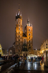 Obraz premium Christmas tree near Saint Mary's Basilica in Krakow Poland. Traditional winter markets with people, horse rides, hot wine and joy.