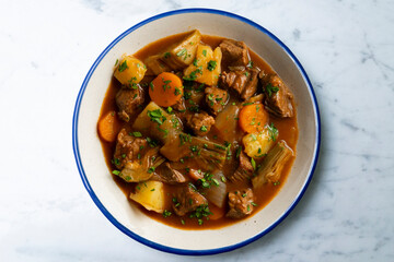 Beef stew with potatoes and artichoke. Top view table with  decoration.