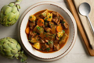 Beef stew with potatoes and artichoke. Top view table with  decoration.