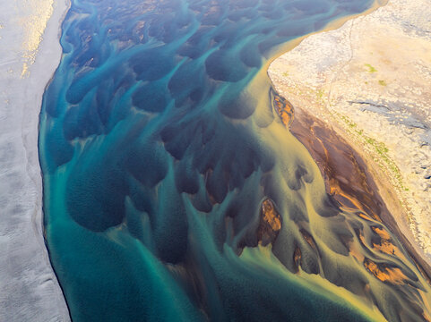Aerial view of vibrant patterns of a river flowing through pristine sand, Hvolsvollur, Iceland.