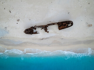 Aerial view of a beautiful sandy beach with a shipwreck and turquoise ocean waves, Volimes, Greece.