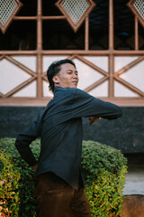 A Southeast Asian man is stretching his back while pushing his hips forward.