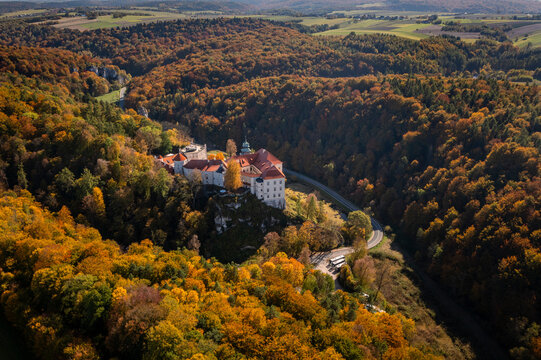 Aerial view of Pieskowa Skala castle surrounded by vibrant autumn foliage in the Pradnik valley, Suloszowa, Poland.