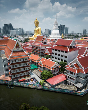 Aerial view of a beautiful buddhist temple with a golden buddha and urban skyline, Phasi Charoen, Thailand.