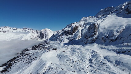 Fototapeta premium Joli paysage de montagnes enneigées dans la campagne française, sur les pistes de la station de ski de Vaujany, près de Grenoble, pendant un beau jour ensoleillé au sommet des pistes.