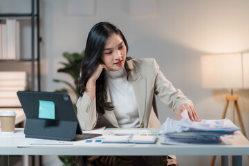 Businesswoman Working Late: A focused young businesswoman diligently works at her desk late into the night, surrounded by paperwork and technology. The image conveys a sense of dedication, hard work, 