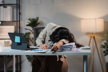 The Weight of Overwork: Exhausted businesswoman slumped over her desk, overwhelmed by paperwork and...