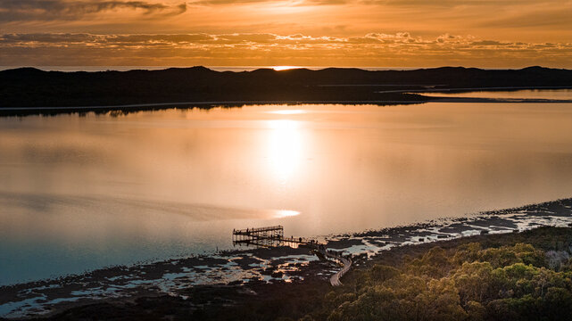 Aerial view of serene Lake Clifton at sunset with beautiful reflections and tranquil sky, Herron, Australia.