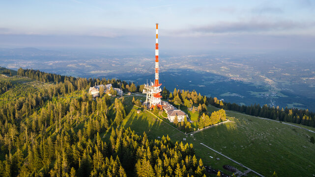 Aerial view of the serene Schoeckl mountain with a communication antenna surrounded by tranquil forest and green valley, Graz, Austria. - Powered by Adobe