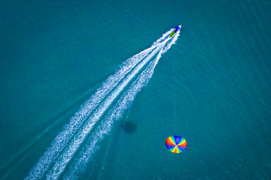 Aerial view of colorful boats parasailing over the beautiful ocean at Pantai Cenang, Kampung Lubok Buaya, Malaysia.