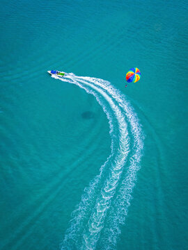 Aerial view of colorful boats and parasailing over the tranquil ocean at Pantai Cenang, Kampung Lubok Buaya, Malaysia.