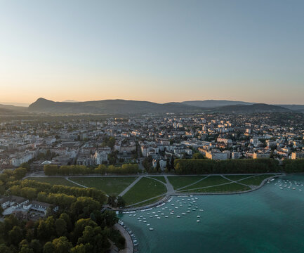 Aerial view of serene Annecy Lake surrounded by beautiful mountains and cityscape at dusk, Marquisats, France.