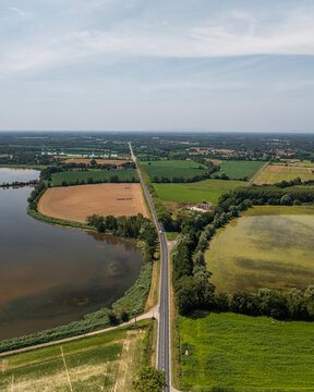 Aerial view of serene Parc des Oiseaux with lush greenery, tranquil lake, and picturesque fields, Marlieux, France.