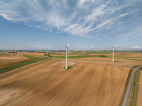 Aerial view of wind turbines in a scenic rural landscape with green fields under a blue sky, Son, Ardennes, France.